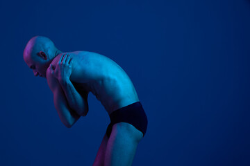 Male figure in blue light, showcasing an artistic pose. The image focuses on body expression and...