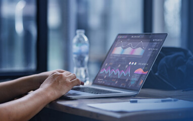 Hands using laptop reviewing digital financial graphs and reports.