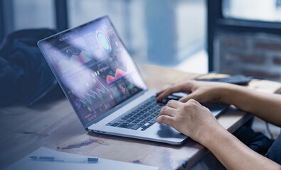 Hands using laptop reviewing digital financial graphs and reports.