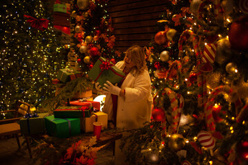 Plus size woman walks around the city during the Christmas of the week with a hot drink in a glass against the background of flickering light bulbs