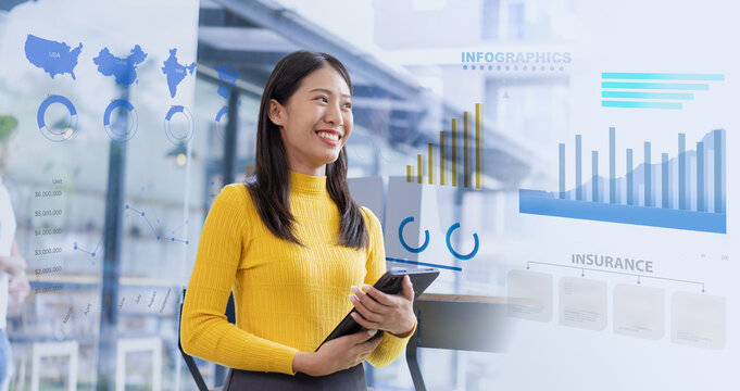 Happy young Asian businesswoman holding digital tablet standing presenting by data analysis chart in office.