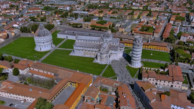 Captivating aerial footage of Pisa&rsquo;s Piazza dei Miracoli showcasing the iconic Leaning Tower, Baptistery and Cathedral amid lush green lawns, terracotta rooftops and Tuscan hills, Italy.