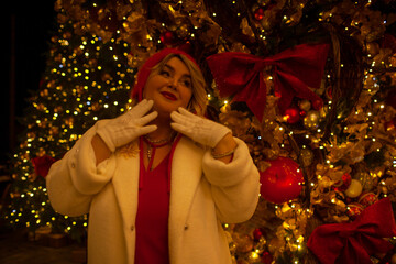 Plus size woman walks around the city during the Christmas of the week with a hot drink in a glass against the background of flickering light bulbs