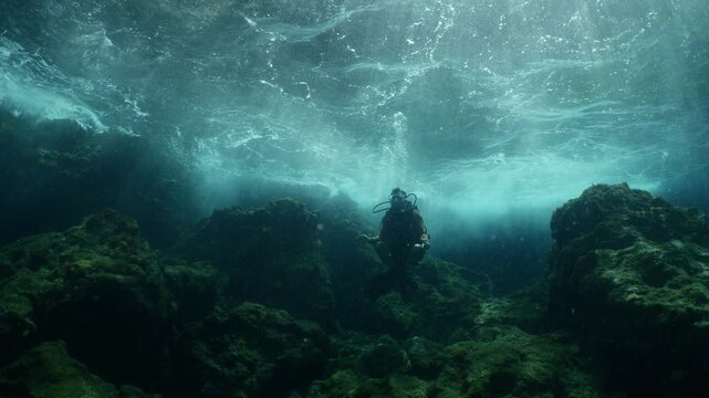 scuba diver howers like budha underwater with waves under sun beams and rays yogo meditation
