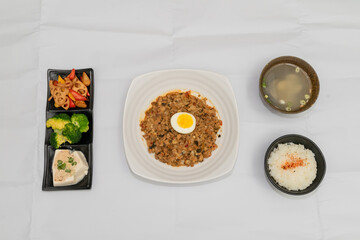 A Thai basil minced pork set meal arranged on a tray, including a portion of stir-fried spicy basil...