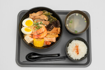 A hearty bowl of seafood noodle soup filled with shrimp, corn, egg, vegetables, rice blood cake,...