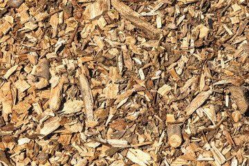 Detailed texture of dry wood chips in natural sunlight, ideal for backgrounds, biomass, gardening,...