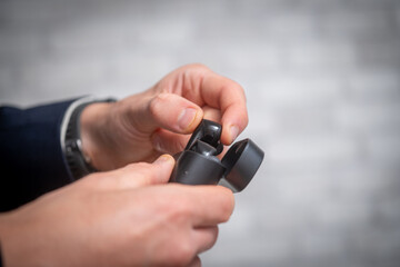 Man taking wireless earbuds out of charging case. Modern technology and lifestyle concept. Close-up of male hands using portable audio device
