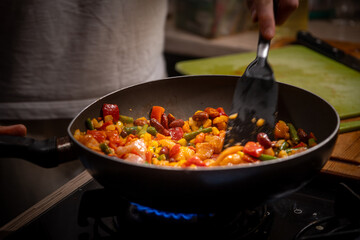 Preparing a healthy, balanced meal: frying frozen vegetables and chicken in a pan. Nutritious cooking, clean eating, and wholesome diet concept for a healthy lifestyle
