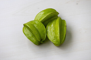 Fresh, vibrant green star fruits (Averrhoa carambola) on a wooden surface. Known as Kamranga in Bangladesh, these tropical delights add a touch of exotic beauty.