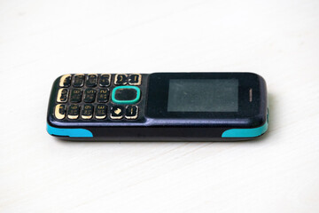 Aged feature phone with worn-out buttons, discolored casing, and scratched screen, showing signs of heavy use. Perfect for themes of technology, nostalgia, and vintage electronics.