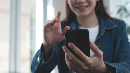 Smiling asian business woman using smartphone for video call at home office, close up