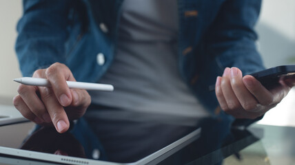 Close up of young asian business woman in casual wear using digital tablet with laptop computer on...