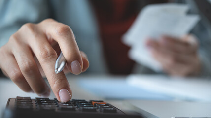 Doing finance, budgeting and tax calculation. Close up woman hand using calculator to calculate...