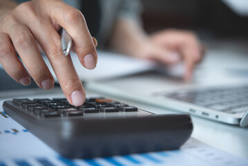 Close-up of businesswoman hands using calculator to calculate company finances, earnings and...