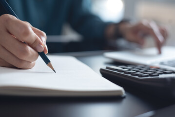 Woman using laptop computer searching ideas and making a note on notebook. Business woman working on laptop and planning, writing on notepad. Student studying online class, e-learning