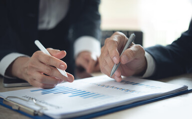 Two business person coworkers working together, analyzing financial report, using digital tablet and having a discussion at office. Business colleague meeting and reviewing marketing report, closeup