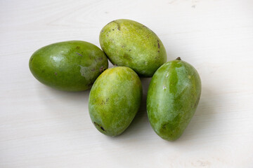 Vibrant four whole fresh ripe Amrapali mangoes on light wooden surface. Emphasize healthy fruit, healthy diet, and organic food photography. Sweet and juicy.