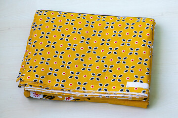 Neatly folded floral printed cotton bed sheet, freshly ironed, showcasing soft fabric texture and...