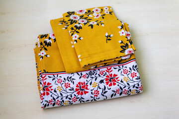 Detailed shot of a freshly ironed, perfectly folded bed sheet and matching pillow cover. The elegant floral pattern on the soft cotton fabric highlights comfort and domestic harmony.