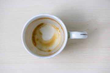 Close-up of an empty white ceramic mug with residual coffee or tea stains, viewed from above. Perfect for beverage, morning, or kitchen concepts, highlighting realistic used drinkware.