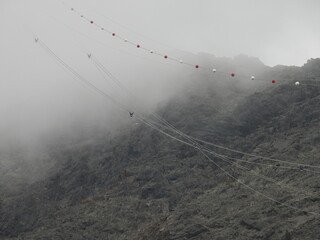 Führungsseile einer Seilbahn verschwinden in den Wolken