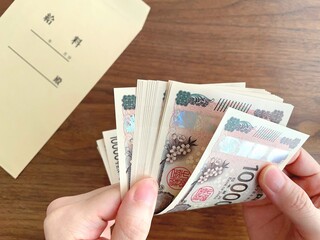 机上の給料袋と紙幣を数える女性の手
