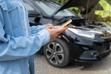 breakdown, broken car, repair. Woman uses mobile phone check insurance premiums through application...