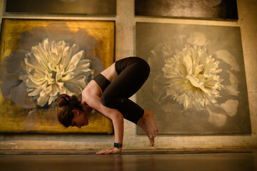 Young woman practicing yoga poses in an art gallery space, combining wellness and creativity. Mindful lifestyle, body awareness, and harmony in modern cultural environment