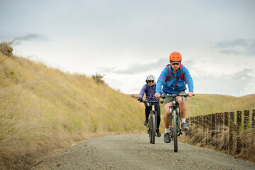 Low angle view of couple riding on gravel bike track. Otago Central Rail Trail. South Island. New...