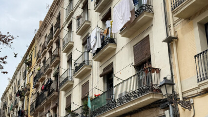 Urban tapestry of laundry-laden balconies, bustling with Mediterranean charm, echoes of La Tomatina, subtle rhythms of Fiesta Nacional patches
