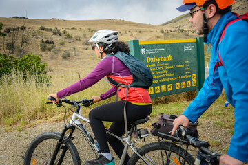 Couple riding past Daisybank sign. Otago Central Rail Trail. South Island.