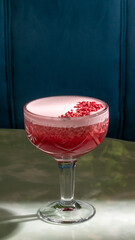 Crimson cocktail in vintage glass unveils pomegranate froth, evoking Valentine's soirees and midsummer night escapades