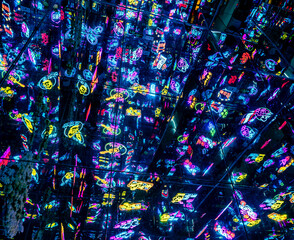 a neon-lit, densely packed urban nightlife scene. The scene is filled with various signs...