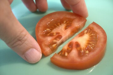 Two half round slices of red tomato placed on a bright blue background. Clean and vibrant food...