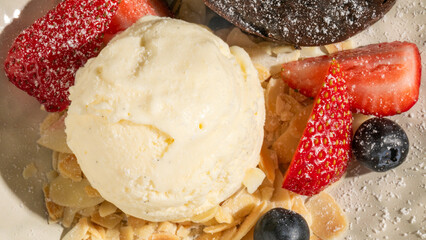 Creamy vanilla scoop atop almond slivers with berries, evoking Nieve de San Juan's sweet midsummer...