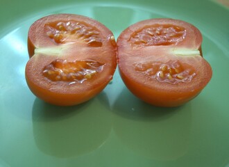 Two halves of a juicy red tomato on a bright blue background. Fresh and simple food composition...