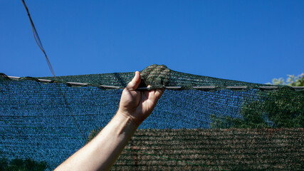 A Caucasian male hand levitates a steadfast stone over taut netting, evoking the enigmatic spirit...