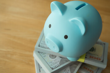 Blue piggy bank on stack US dollar bill banknotes. Wealth management, money saving, personal...