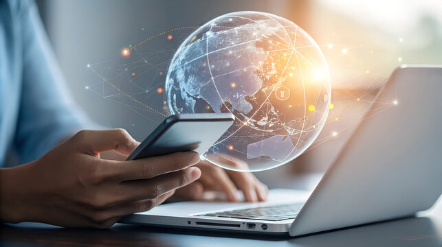 Person using smartphone and laptop with holographic globe overlay