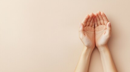 Woman's hands cupped together in front of a blank beige background.