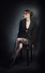 Sensual portrait of young woman in dark suit and fishnet tights.