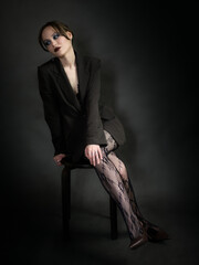 Sensual portrait of young woman in dark suit and fishnet tights.