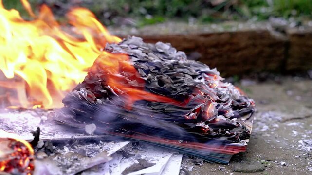 Bright flame with strong wind. Burning of books and papers lying on the ground.