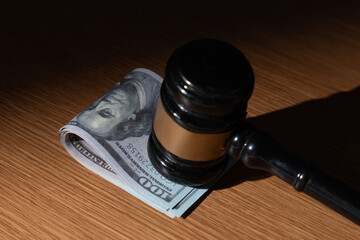 A stack of U.S. hundred-dollar bills and a gavel. Bribery, corruption, or legal dealings involving...