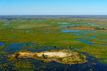 Obraz premium Breathtaking aerial view of the Okavango Delta near Maun in Botswana, showing vibrant wetlands, blue lagoons, and golden grasslands. Ideal for use in nature, travel, and wildlife photography projects.