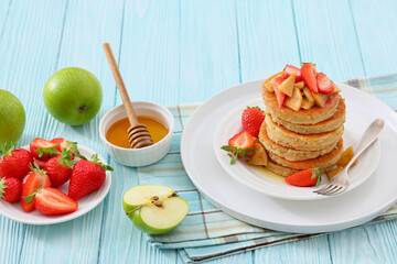 pancakes topped with apple slices and strawberries
