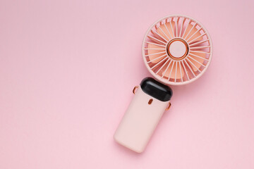 Portable Pink Handheld Fan on Minimalist Pastel Background for Summer Cooling © kvladimirv