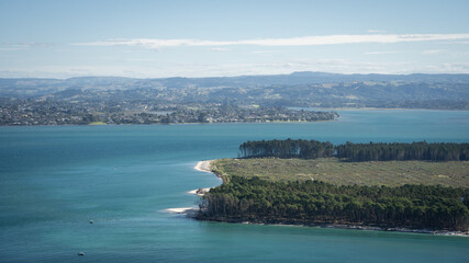 Marine bay with green peninsula, costal city and mountains in backdrop, Tauranga, New Zealand