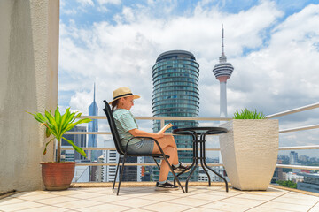 Woman is reading a book at scenic terrace among skyscrapers